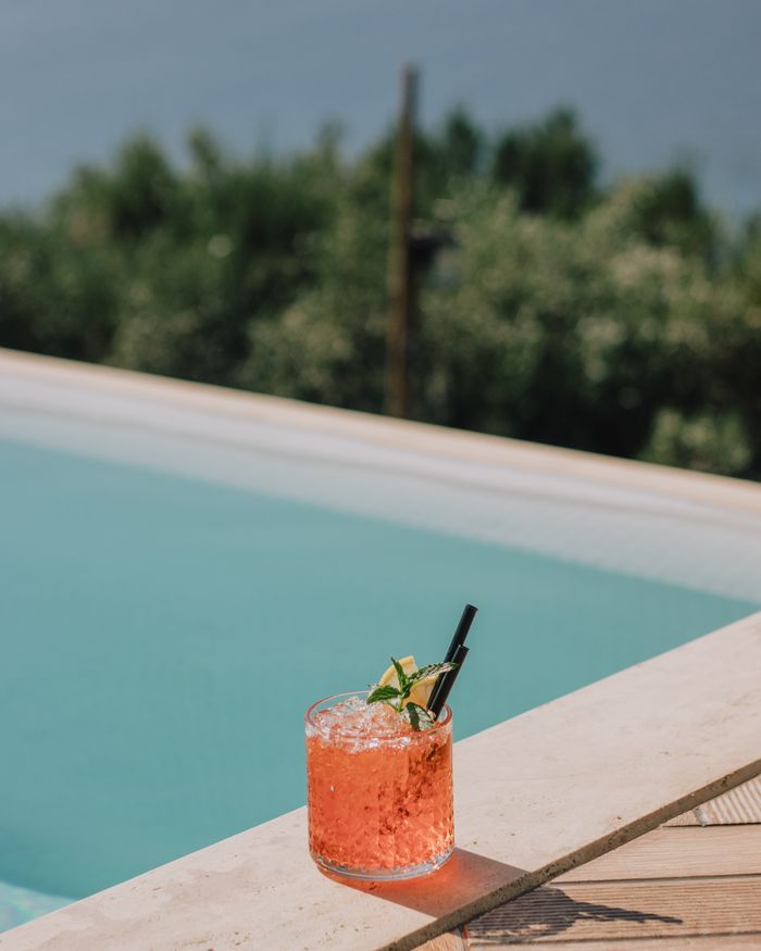 Chilled cocktail with garnish on a pool edge, perfect for summer relaxation outdoors.